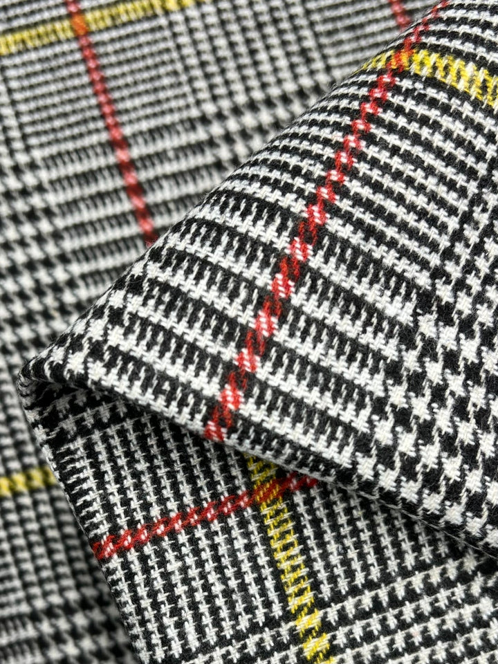 Close-up of Super Cheap Fabrics' premium Wool Flannel - Redellow Plaid (150cm), featuring a black and white houndstooth pattern with striking red and yellow lines overlaid, highlighting the elegance of designer wool fabrics.