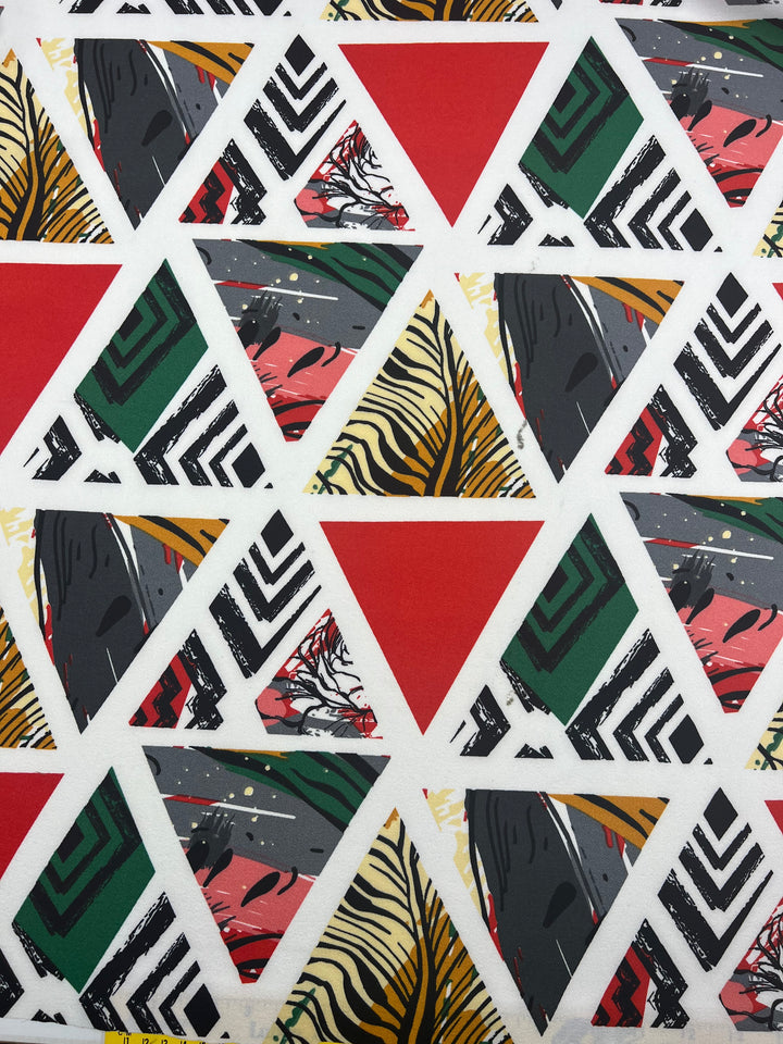 The Printed Crepe - Windows by Super Cheap Fabrics features a vibrant geometric design with red triangles, black-and-white stripes, zebra patterns, and abstract green, pink, and gray motifs. Covering the lightweight polyester fabric, this mosaic adds dynamic flair to any setting. Width: 150cm.