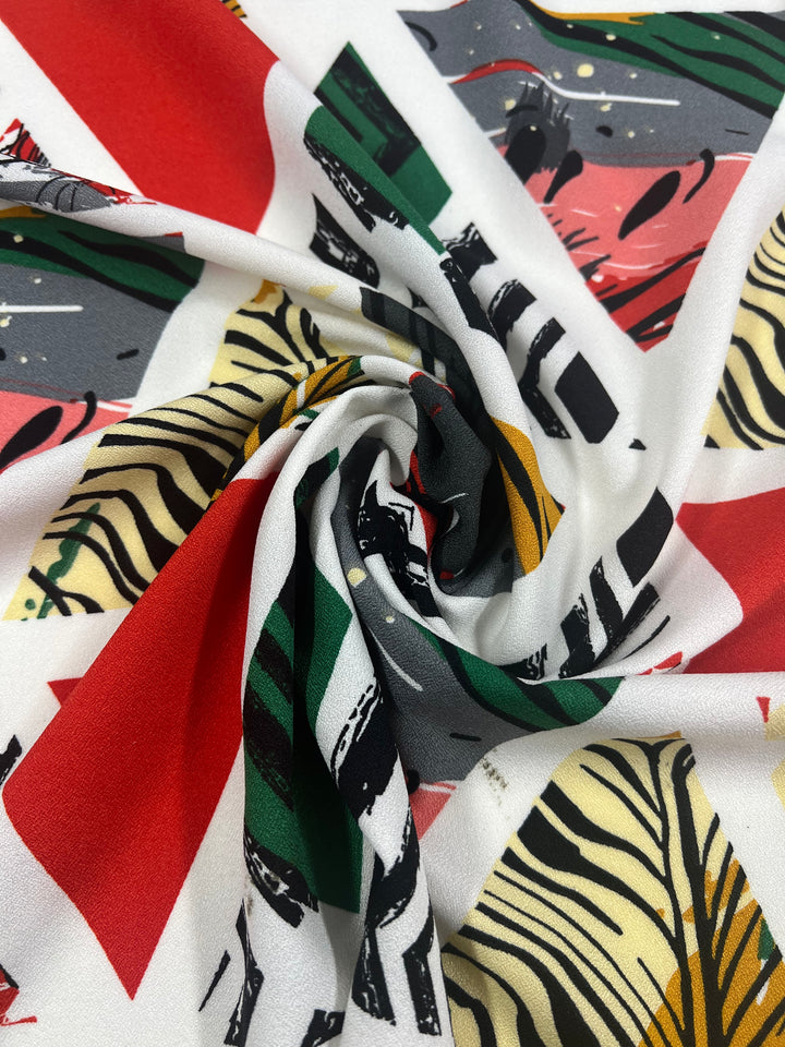 A close-up of Printed Crepe - Windows by Super Cheap Fabrics showcases swirling bold geometric patterns and abstract designs in red, green, yellow, black, and white. This lightweight polyester fabric also highlights a striking zebra stripe motif. Width: 150cm.