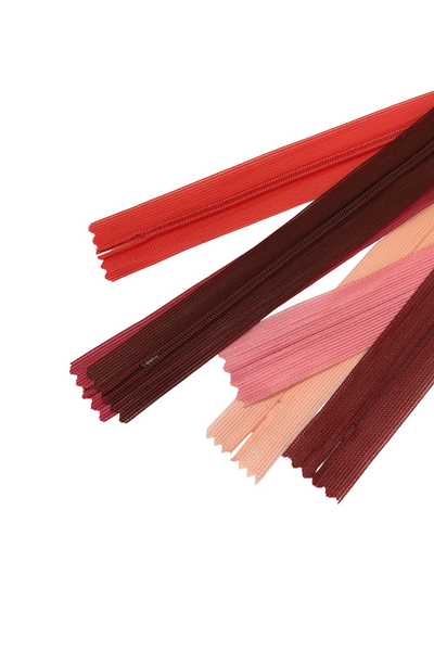 Super Cheap Fabrics’ Invisible Zip - 30cm - Pinks & Reds features overlapping 100% polyester zippers in red, pink, and burgundy, arranged diagonally on a white background.